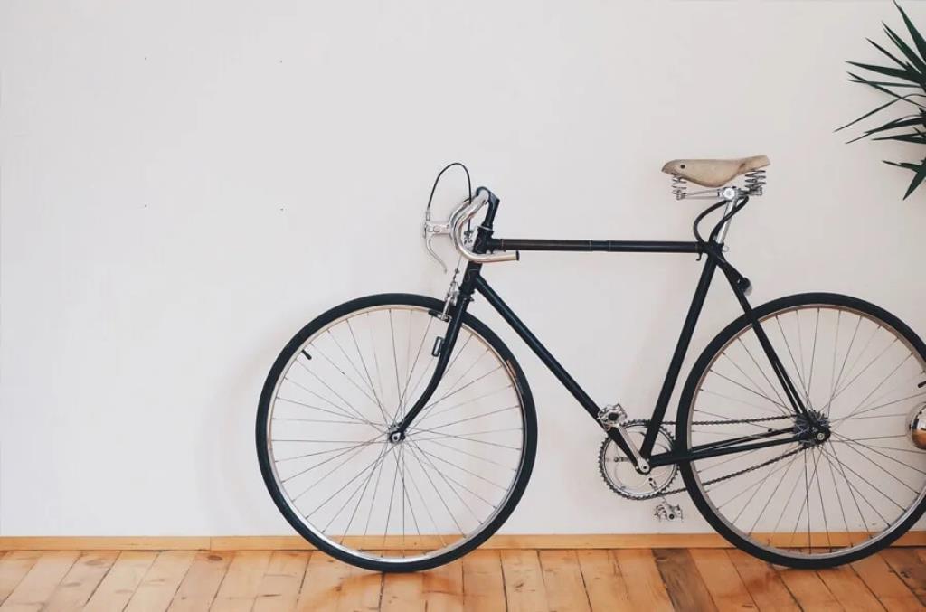 Imagem de uma bicicleta preta encostada em uma parede cinza-claro