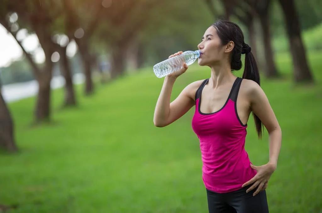 Mulher em um parque bebendo uma garrafa d'água
