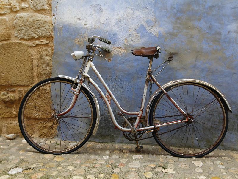 Bicicleta de um modelo antigo, encostada na parede