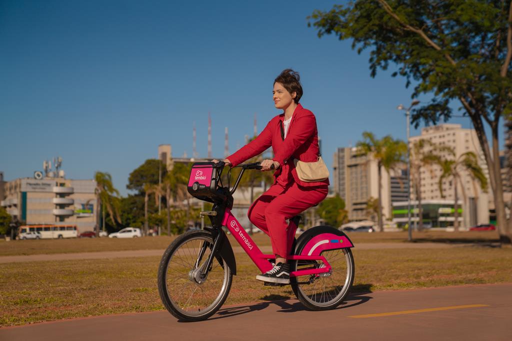 Mulher andando com a bicicleta da Tembici pela ciclovia da cidade.