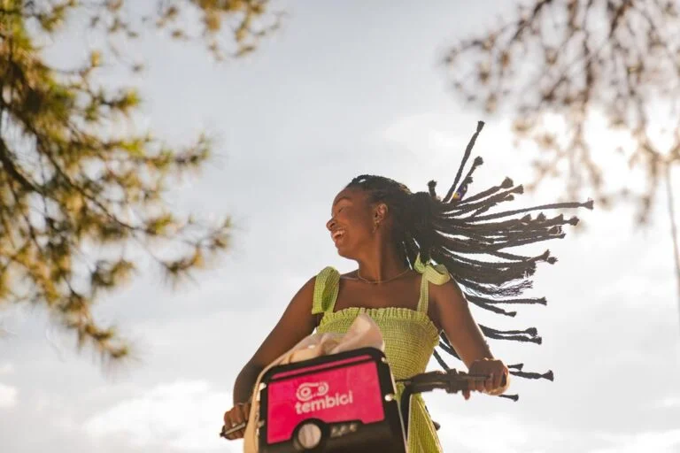 mulher feliz andando com a bike da tembici.