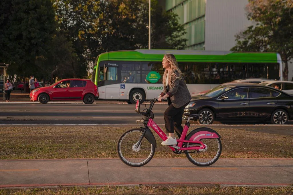 mulher pedalando com bike da tembici em uma ciclovia