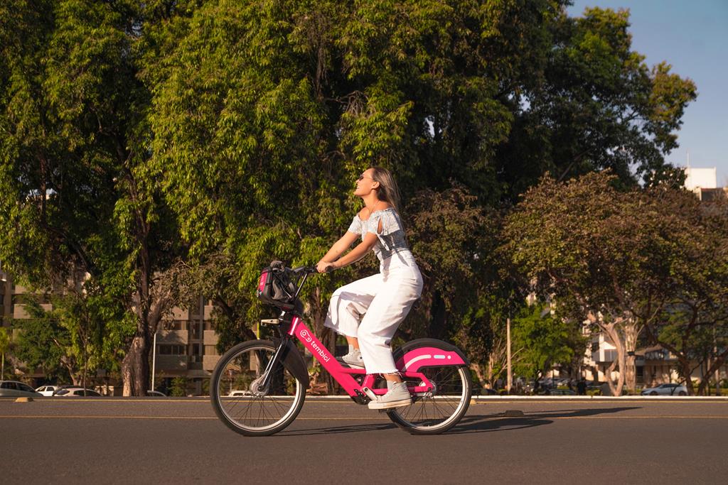 mulher pedalando em áreas urbanas com bike da tembici, respeitando as normas de trânsito.