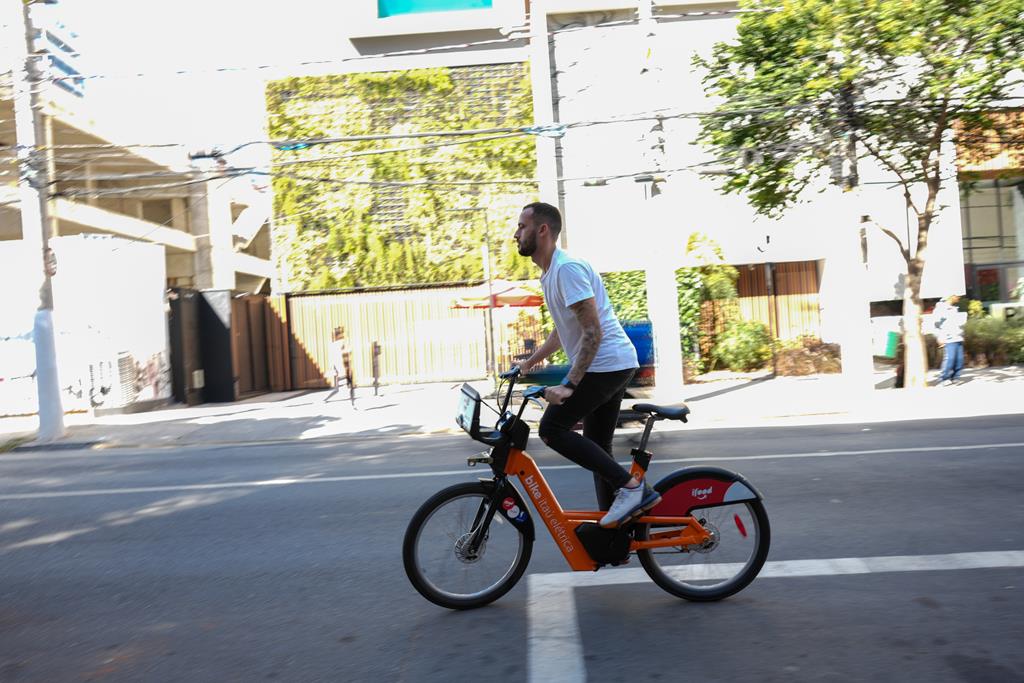jovem andando com uma bike elétrica da Tembici pelas ruas de São Paulo.