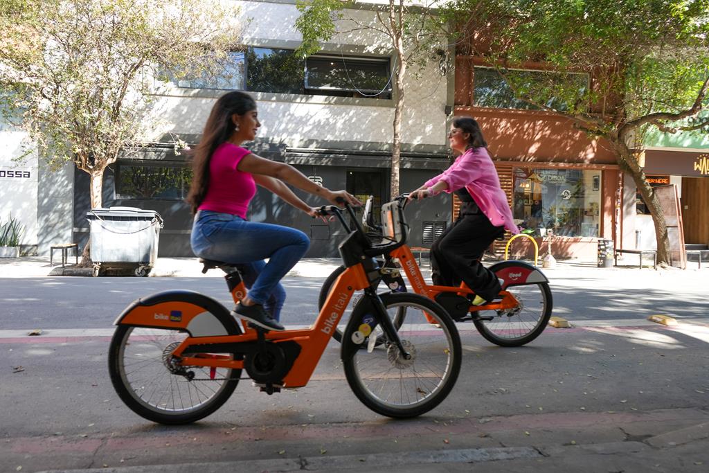 duas mulheres andando com a bicicleta elétrica da Tembici pelas ruas de São Paulo.