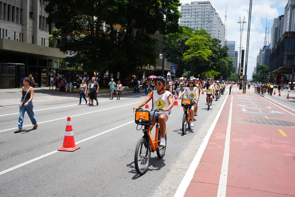 pessoas passeando com bikes da Tembici pelas ruas da cidade de são paulo, e um evento destinado aos ciclistas.