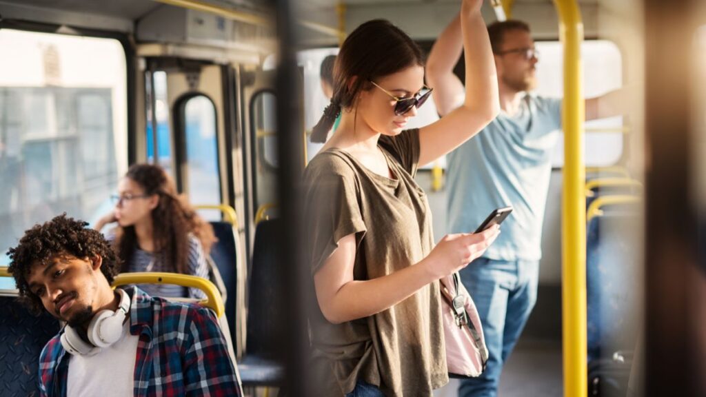 mulher jovem utilizando o telefone celular dentro do transporte público.