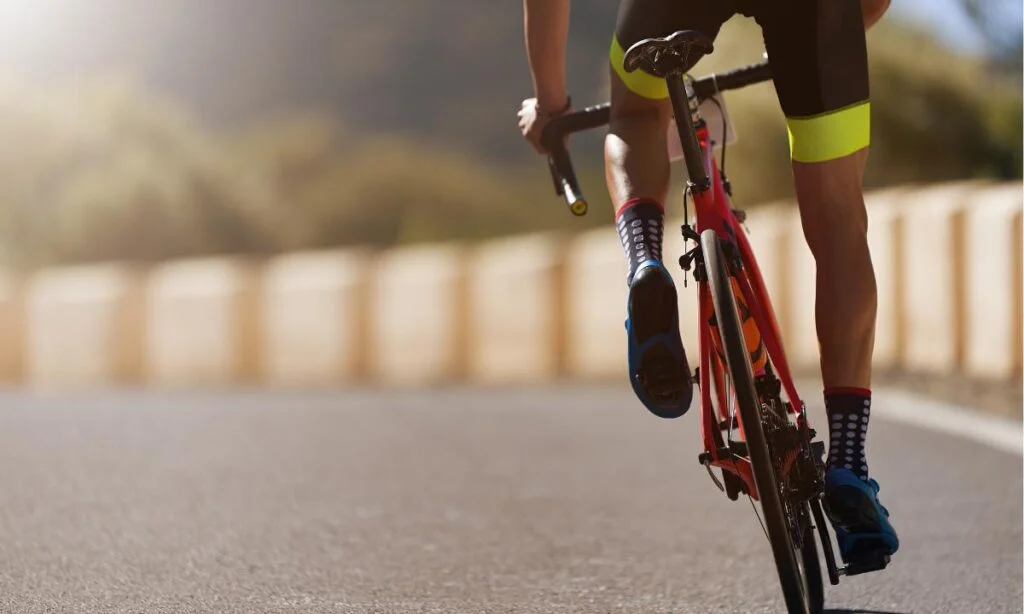 imagem mostrando que pedalar promove o fortalecimento do corpo, homem pedalando em uma estrada