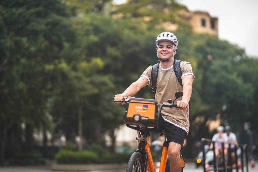 Homem usando bike da Tembici para andar de bicicleta, com os equipamentos de segurança adequados