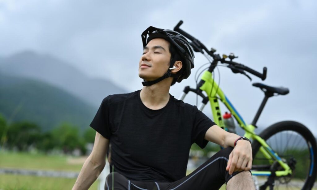 benefícios de pedalar, clicista respirando ao ar livre ao lado de sua bike