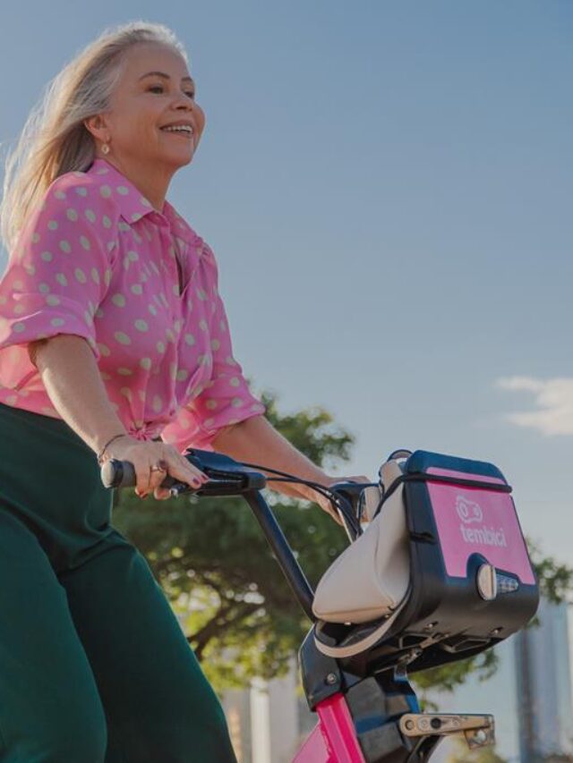 mulher andando de bike em parque em um dia ensolarado.