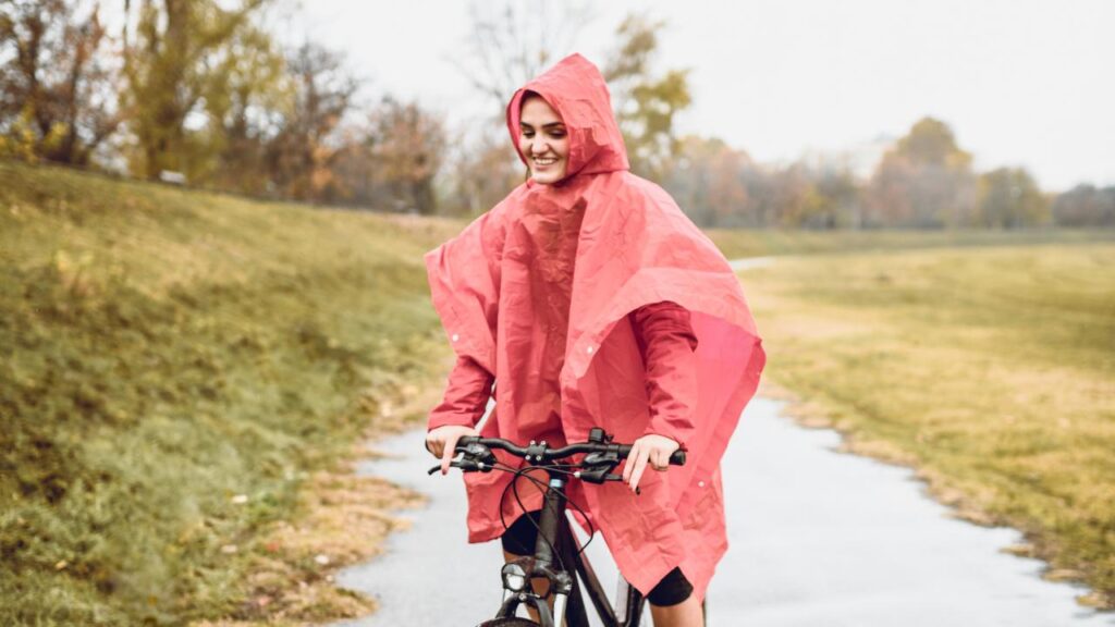 mulher com capa de chuva para se proteger enquanto anda de bicicleta