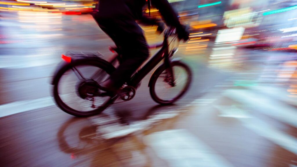 Ciclista com sua bicicleta, a noite em ruas de uma cidade