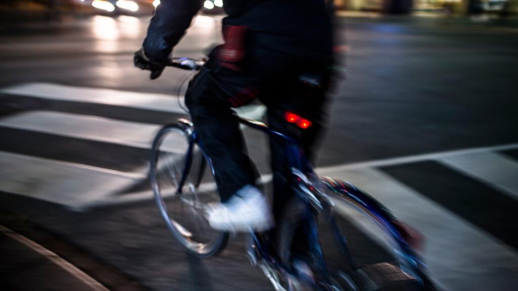 ciclista saindo para pedalar à noite pela cidade com equipamentos de sinalização instalados 