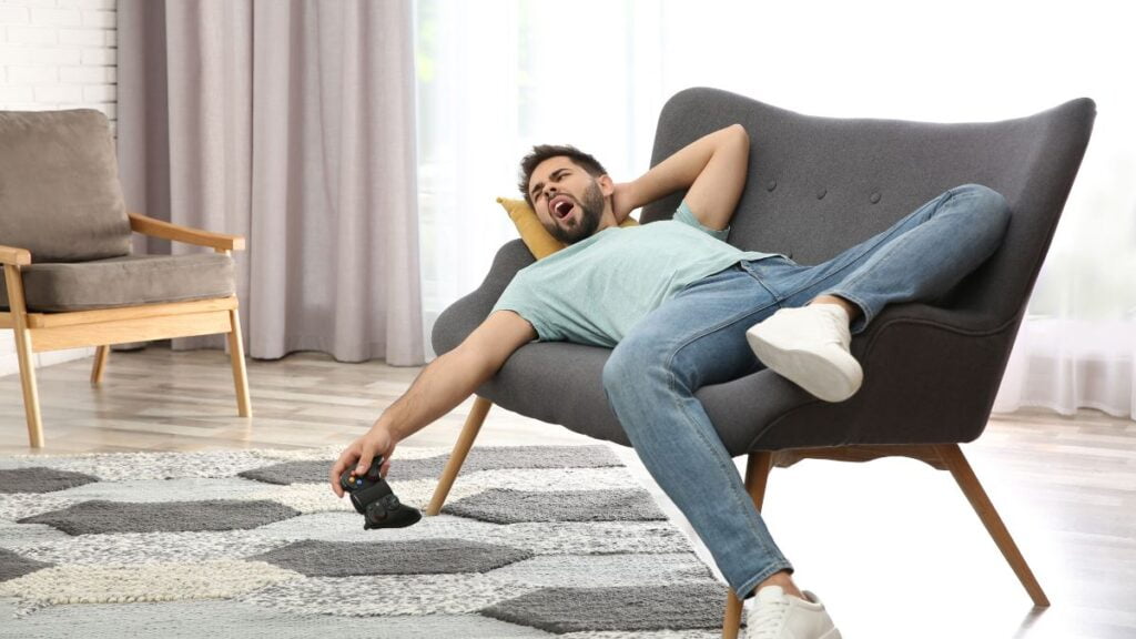 homem deitado em um sofa, cansado enquanto joga video game