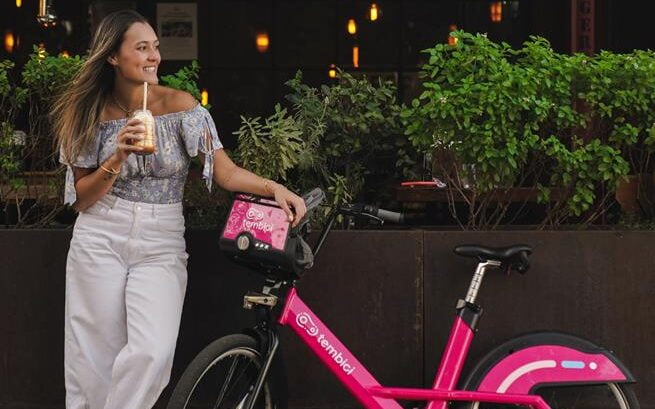 mulher tomando milkshake ao lado da bike tembici