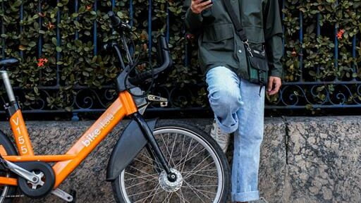 jovem encostado no muro com sua bike da Tembici